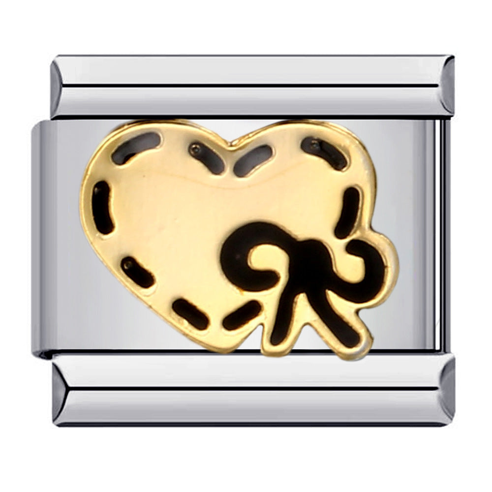 A silver-toned charm link with a shiny gold heart with black stitched details and an adorable black bow. 